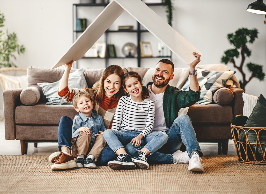 Personal Insurance - A Mother and a Father Smiling Happily With Their Children in the Living Room of Their New House
